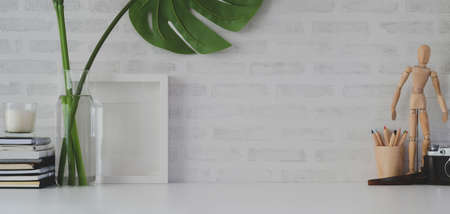 Comfortable workplace with mock up frame and office supplies on white table and white brick wallの写真素材