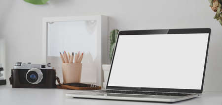 Open blank screen laptop computer in photographer workplace with office suppliesの写真素材