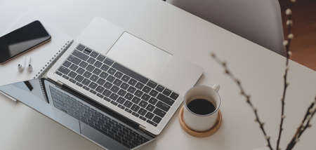 Cropped shot of comfortable workspace with laptop computer and office supplies on white wooden tableの写真素材