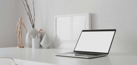 Modern workspace with open blank screen laptop computer and mock up frame with decorations on white wooden tableの写真素材