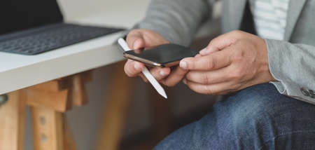 Cropped shot of professional businessman using his smartphone in comfortable office roomの写真素材