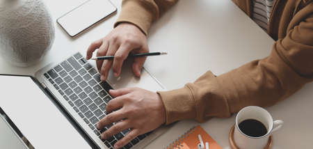 Cropped shot of man working on his project while typing on laptop computer in his comfortable roomの写真素材