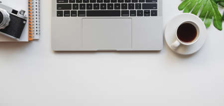 Top view of designer workplace with laptop computer and camera on white table backgroundの写真素材