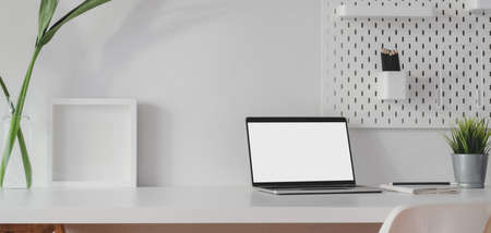 Minimal workspace with open blank screen laptop computer and mock up frame with decorations on white wooden tableの写真素材