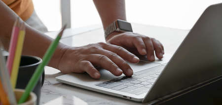 Cropped shot of businessman typing on laptop computer while working on his project in comfortable workplaceの写真素材