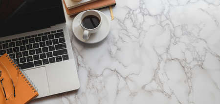 Top view of modern stylish workplace with laptop computer and office supplies on marble table...