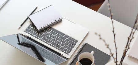 Cropped shot of modern office room with laptop computer and office supplies on white wooden tableの写真素材