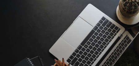Top view of dark modern workplace with laptop computer and office supplies on black table backgroundの写真素材