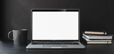 Cropped shot of modern office room with blank screen laptop computer and office supplies on black tableの写真素材