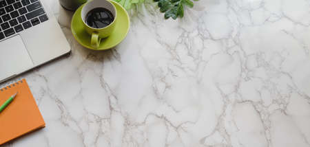 Top view of modern workplace with office supplies and green coffee cup on marble desk backgroundの写真素材