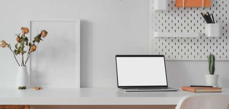 Modern workspace with open blank screen laptop computer and mock up frame with decorations on white wooden tableの写真素材