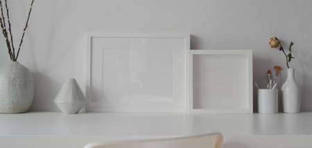 Minimal office room with mock up frames and white ceramic vase decorations on white tableの写真素材