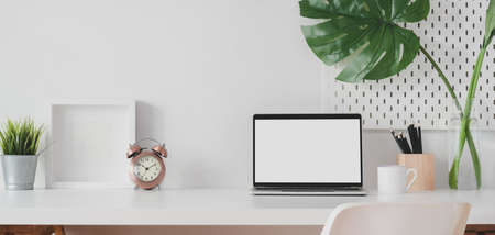Modern workspace with open blank screen laptop computer and mock up frame with decorations on white wooden tableの写真素材
