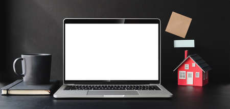 Cropped shot of modern office room with blank screen laptop computer and office supplies on black tableの写真素材