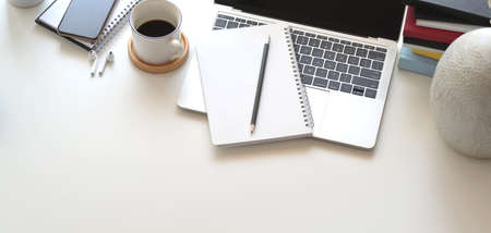 Cropped shot of comfortable workspace with laptop computer and office supplies on white wooden tableの写真素材