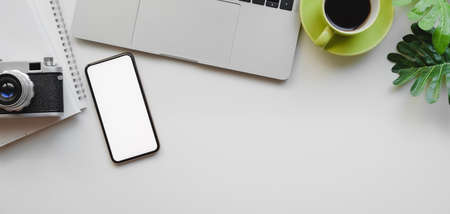 Top view of designer workplace with laptop computer, mock up smartphone and camera on white table backgroundの写真素材