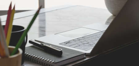 Close-up view of comfortable workplace with laptop computer and office supplies near the windowsの写真素材