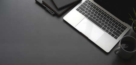 Overhead shot of dark stylish workspace with laptop computer black notebook on black table backgroundの写真素材