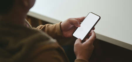 Cropped shot of young man using blank screen smartphone in his modern workplace