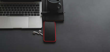 Overhead shot of laptop computer and smartphone with copy space on black table background