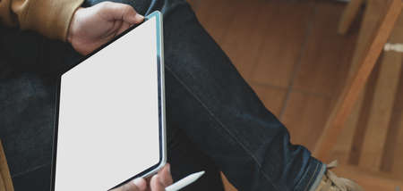 Close-up view of passionate freelancer working on his project while writing on blank screen tabletの写真素材