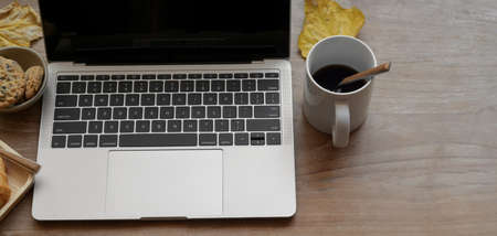 Top view of comfortable workplace with laptop computer and coffee cup on wooden table with copy spaceの写真素材