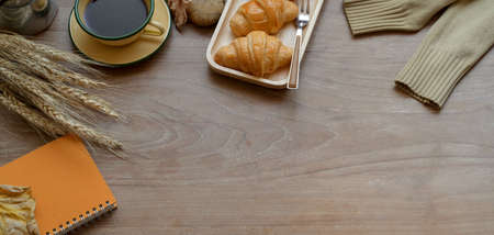 Overhead shot of cozy workplace with breakfast and office supplies on wooden table with copy spaceの写真素材