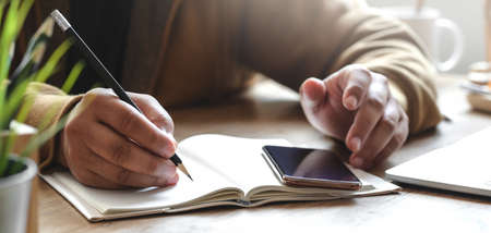 Close-up view young man working on his project with smartphone in comfortable office roomの写真素材