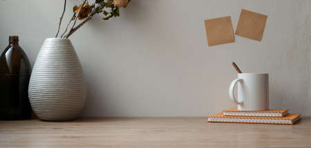 Vintage workspace with dry roses with office supplies and copy space on wooden table and sticky note on the wallの写真素材