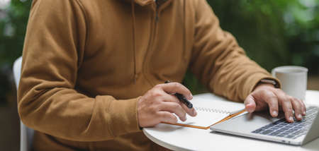 Close-up view of man working with laptop computer in outdoor comfortable workplace