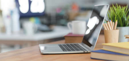 Cropped shot of laptop computer in comfortable workplace with blurred office backgroundの写真素材