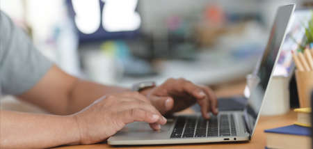 Cropped shot of businessman typing on laptop computer in comfortable workplace with blurred office backgroundの写真素材