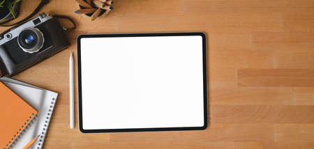 Overhead shot of contemporary workplace with blank screen digital tablet on wooden tableの写真素材