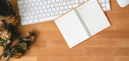 Top view of comfortable workplace with notebook and keyboard computer on wooden table with dry roses decorationsの写真素材