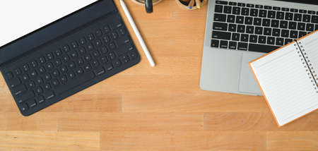 Top view of modern workspace with laptop computer and tablet with office supplies on wooden table...