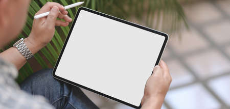 Cropped of young professional businessman using blank screen digital tablet while working on his projectの写真素材