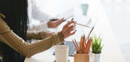 Cropped shot of professional business team discussing the project together while using tablet in modern office roomの写真素材