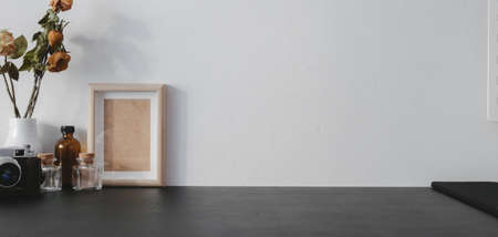 Cropped shot of modern workplace with copy space and office supplies on black table and white wall...