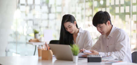 Close-up view of two young passionate designer team discussing the project together in modern office...
