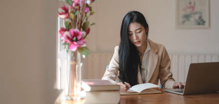 Portrait of beautiful businesswoman working on her new project while readingInformation from books...