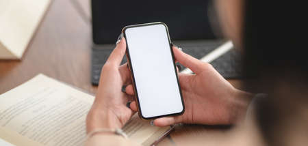 Close-up view of young businesswoman working on her project while using smartphone in comfortable...