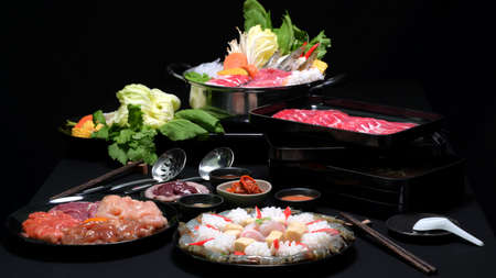Set of shabu shabu in hot pot, fresh sliced meat, sea food and vegetables with black background, Japanese hotpot styleの写真素材