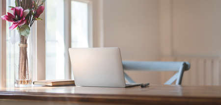 Cropped shot of comfortable workplace with laptop computer and office supplies on wooden table next...
