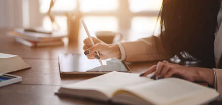 Close-up view of young professional businesswoman working on her project while using digital tablet