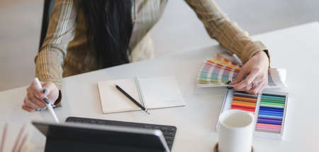 Cropped shot of beautiful  designer working on her project with digital tablet in modern workplaceの写真素材