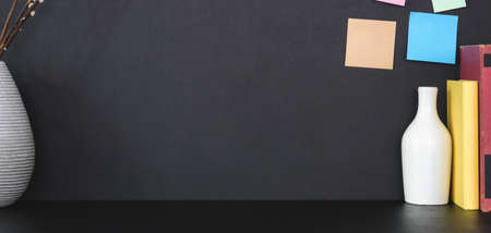 Close-up view of modern workplace with office supplies and sticky note on black table with black...