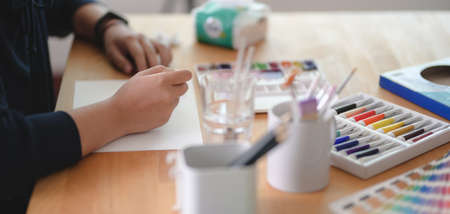 Cropped shot of young artist painting on sketch paper with water colour in comfortable workplaceの写真素材