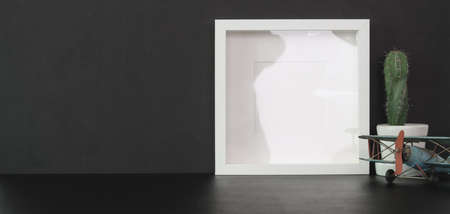 Cropped shot of trendy office room with mock up frame and copy space on black table with black wall backgroundの写真素材