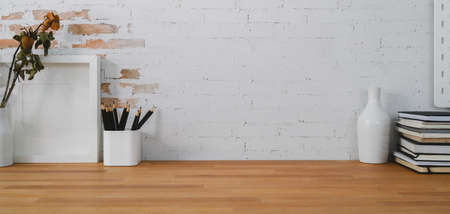 Cropped shot of comfortable workplace with mock up frame, office supplies and copy space on wooden...