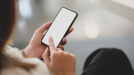Cropped shot of young businesswoman using blank screen smartphone in modern office room 